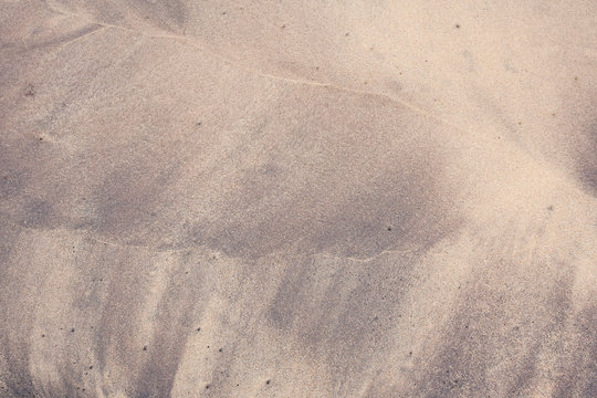 Beach pattern by waves on sand - Purple curved beach patterns on a tropical beach. These colorful patterns on the beach are created by the waves with orange sand and black silt deposits from the sea.