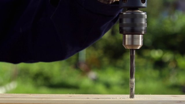 Drilling wooden plank with hand drill, closeup
