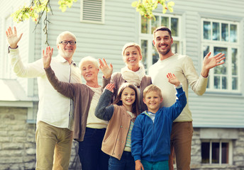 happy family waving hands in front of house