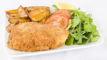 Wiener Schnitzel - Veal steak breaded and fried in butter served with salad, potato wedges and a lemon slice.