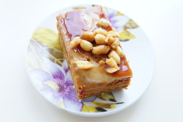 Пирожное залитое глазурью с арахисом на маленьком блюдце