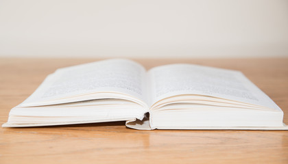 White open book on wooden table with soft focus