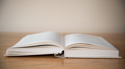 White open book on wooden table with soft focus