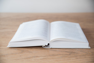 White open book on wooden table with soft focus