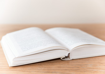 White open book on wooden table with soft focus