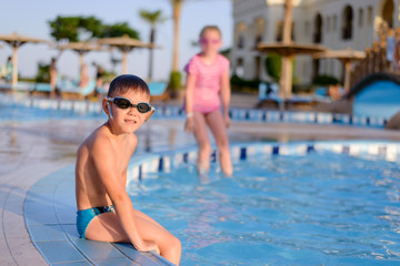 Young boy sitting at the side of a pool
