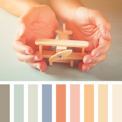 close up photo of man's hand holding wooden  airplane with palette color swatches
