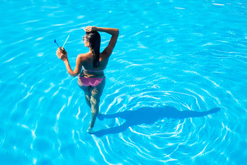 Back view portrait of a woman standing in swim pool