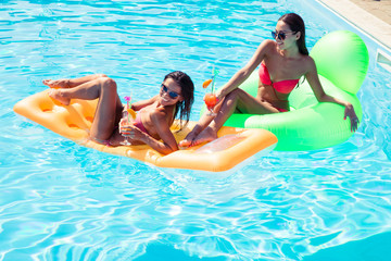 Girls resting on air mattress in swimming pool