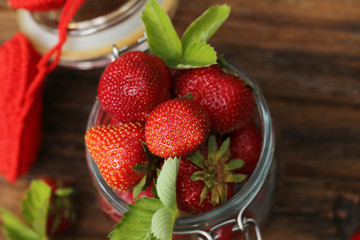 strawberries in a glass jar and an old wooden background retro vintage