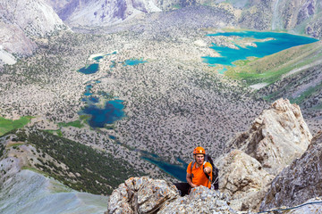 Mountain guide pointing Mature mountain guide leading his team pointing with his hand best way to go hanging over deep abyss with vivid blue lakes on blurred background