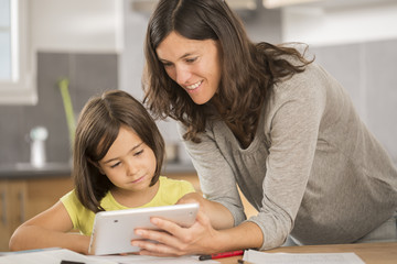 mother and daughter doing homework with a tablet