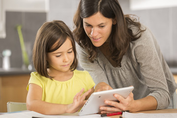 mother and daughter doing homework with a tablet
