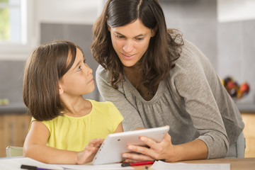 mother and daughter doing homework with a tablet