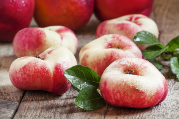 Flat Nectarines with leaves on the old wooden table, selective f