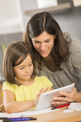 mother and daughter doing homework with a tablet