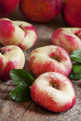 Flat Nectarines with leaves on the old wooden table, selective f