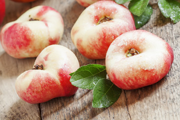 Flat Nectarines with leaves on the old wooden table, selective f