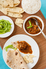Mutton rogan josh meal - Tasting Indian mutton rogan josh meal with rice and chapati. This spicy hot Kashmiri dish uses red chilli (cayenne pepper) as its main ingredient. Natural light used.