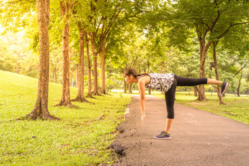 Fototapeta premium Side view of woman runner stretching warm up with single-leg dea