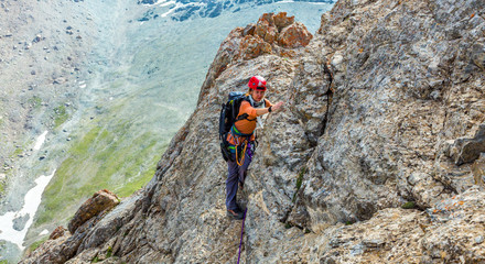 Person climbs mountain
Female mountain climber traversing bright orange red rock moving towards...
