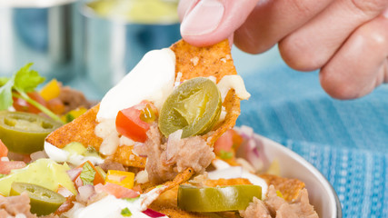 Nachos - Cheesy nachos topped with sour cream, refried beans, pico de gallo, jalapenos and...
