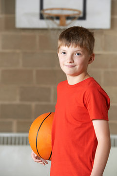 Portrait Of Boy Holding Basketball In School Gym