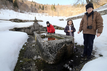 Three children near a Large monumental fountain with cold water