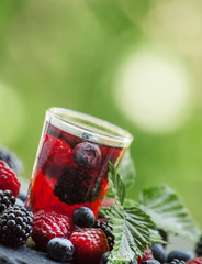 Tea with forest berries on a green natural background, selective
