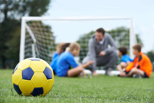 Fototapeta Coach  And Team Discussing Soccer Tactics With Ball In Foregroun