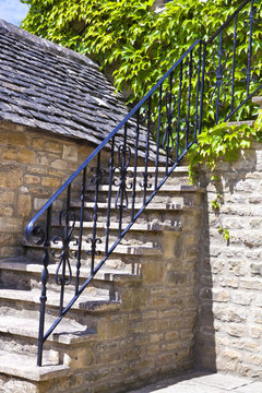 stone stair case in old cottage, metal railings, green vine grape plant