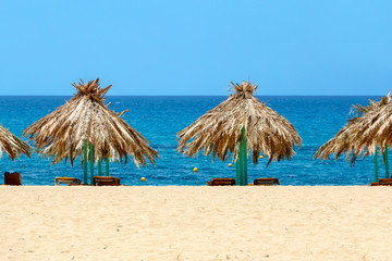 Fototapeta na wymiar Blue sea, golden sand and sunbeds on the beach