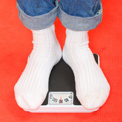 Overweight woman in socks standing on a weighing machine. 