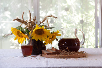kvass (kvas) in a transparent jug, rye bread and a bouquet of su