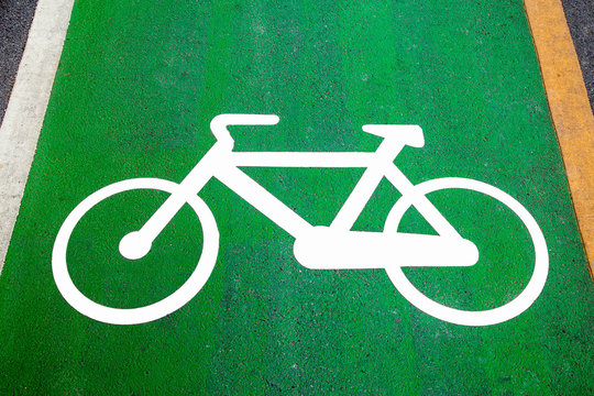 Fototapeta Bike lane signs painted onto a green bike lane (Bike lane, road