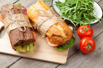 Two sandwiches with salad, ham, cheese and tomatoes
