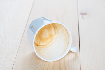 Dirty white mug of coffee lying on the boards