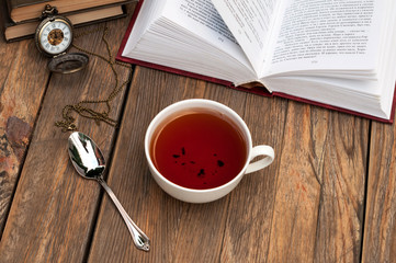 Cup of black tea and some books on the old wooden table