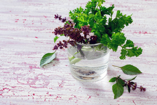 Basil and parsley in a cup on a wooden table