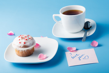 Colorful muffin on saucer with flower petal