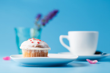 Colorful muffin on saucer with flower petal