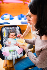 Mutter füttert Baby bei Hebamme