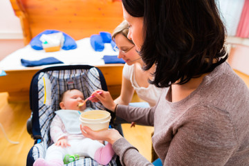 Mutter füttert Baby bei Hebamme
