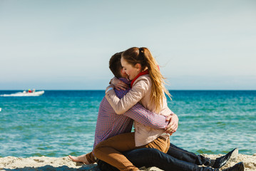 couple sitting on beach relaxing and hugging