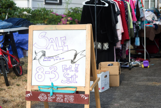 A hand-lettered sign advertises a home garage sale of used items.