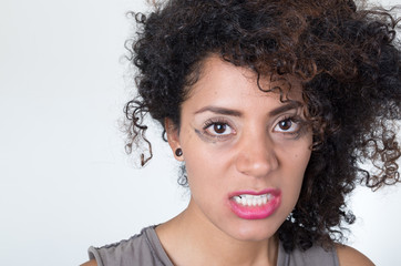 Headshot hispanic brunette model with messy makeup and hair looking angrily into camera, white background