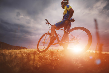 Fototapeta na wymiar mountain bike cyclist riding track on grass rocky trail above su