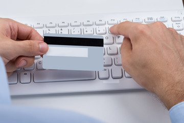 Hands Holding Credit Card On A Keyboard