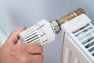 Person Adjusting Temperature Of Radiator Thermostat