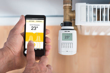 Person Hand Adjusting Temperature Of Thermostat Using Cellphone